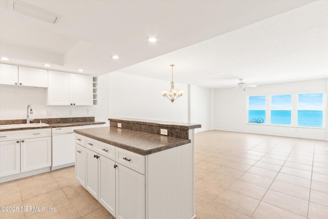 kitchen with white dishwasher, ceiling fan with notable chandelier, white cabinets, and sink