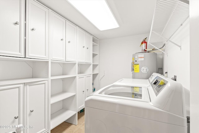 clothes washing area with water heater, cabinets, and independent washer and dryer