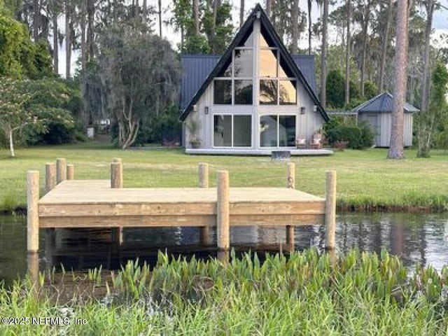 back of house with a water view, a yard, and a shed