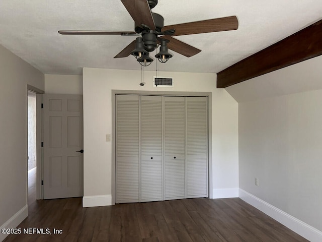 unfurnished bedroom featuring vaulted ceiling with beams, ceiling fan, dark hardwood / wood-style floors, and a closet