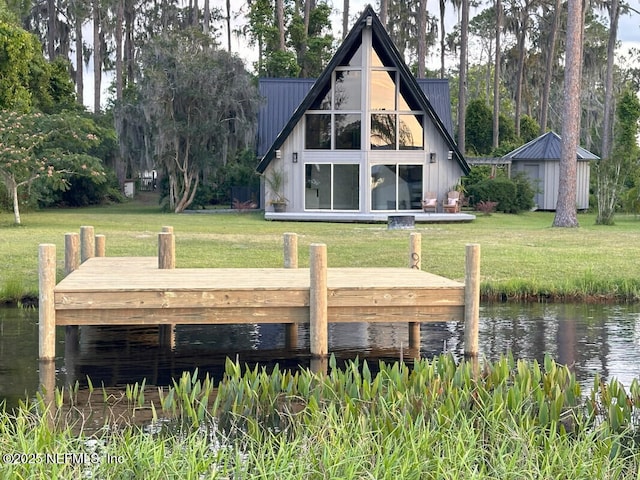 rear view of house featuring a water view and a lawn