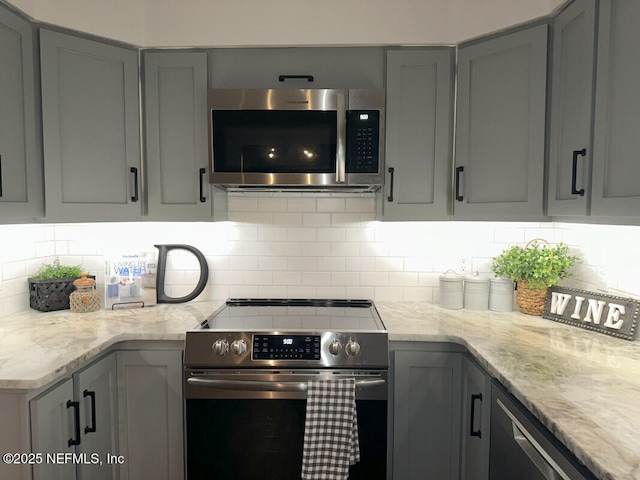 kitchen featuring gray cabinetry, light stone counters, and appliances with stainless steel finishes