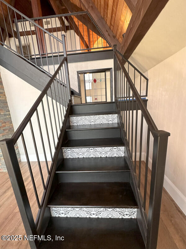 stairway featuring beamed ceiling, hardwood / wood-style floors, high vaulted ceiling, and wooden ceiling