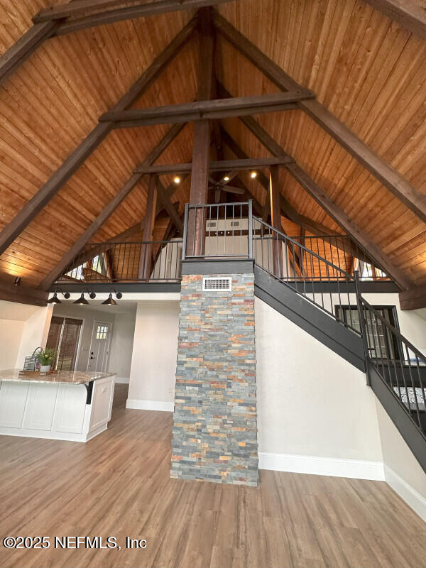 unfurnished living room with beamed ceiling, hardwood / wood-style floors, high vaulted ceiling, and wood ceiling