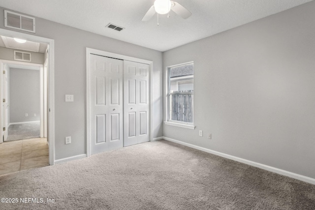 unfurnished bedroom featuring a textured ceiling, a closet, ceiling fan, and carpet