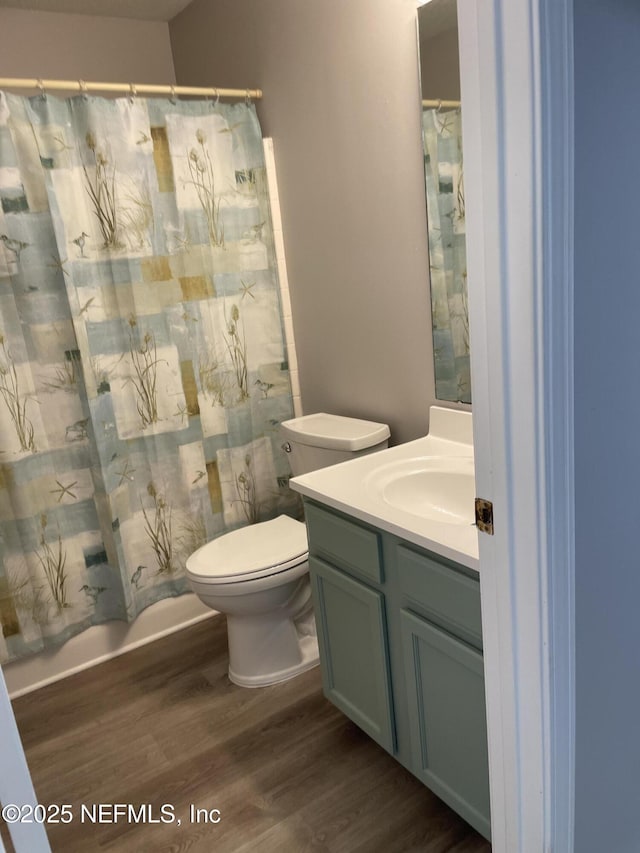 bathroom featuring vanity, hardwood / wood-style flooring, curtained shower, and toilet