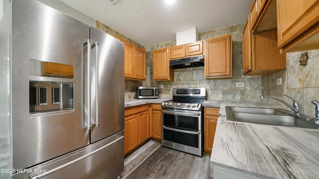 kitchen featuring appliances with stainless steel finishes, backsplash, a textured ceiling, sink, and dark hardwood / wood-style floors