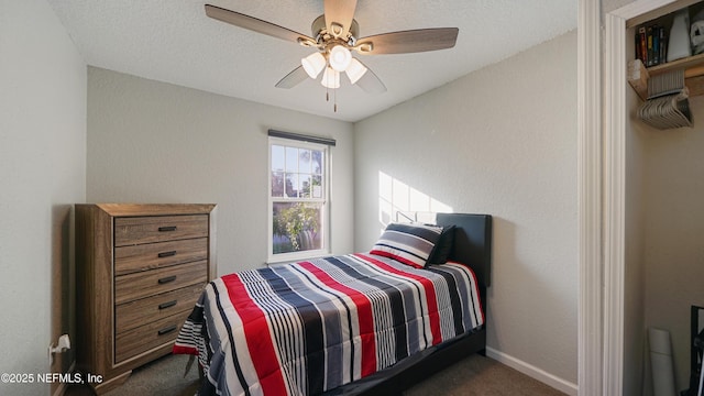 bedroom with ceiling fan, dark carpet, and a textured ceiling