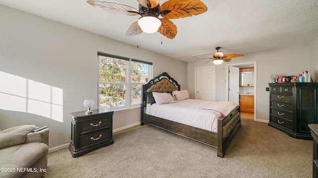 carpeted bedroom with a textured ceiling, ensuite bath, and ceiling fan