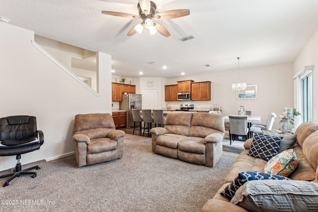 carpeted living room with ceiling fan with notable chandelier and a textured ceiling