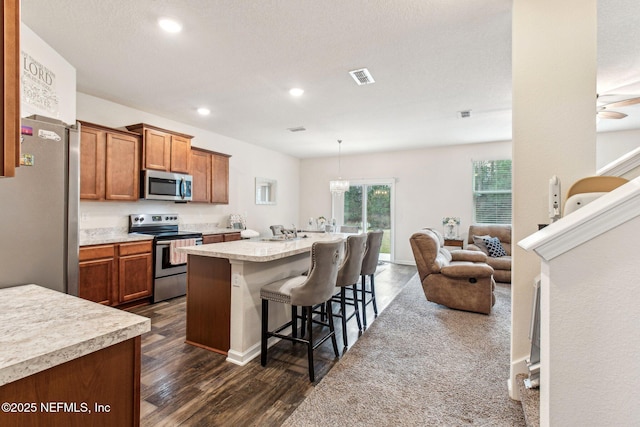 kitchen featuring stainless steel appliances, sink, a kitchen breakfast bar, a center island with sink, and dark wood-type flooring