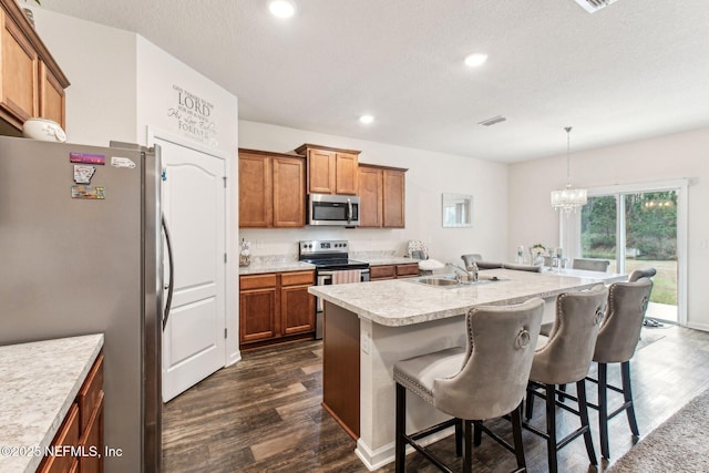 kitchen featuring a breakfast bar area, appliances with stainless steel finishes, an island with sink, pendant lighting, and sink