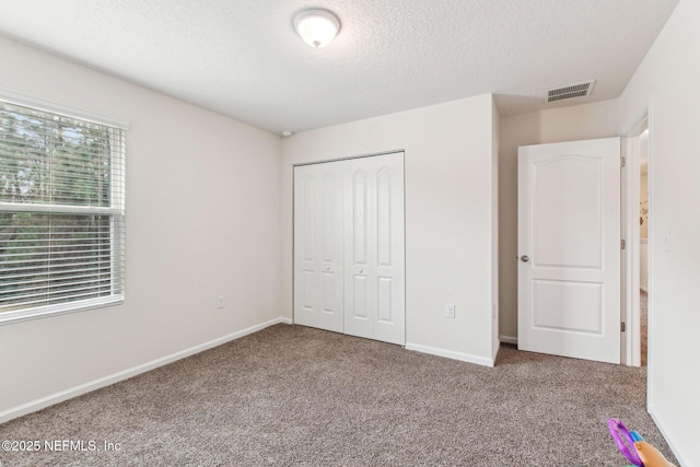 unfurnished bedroom with a textured ceiling, a closet, and carpet