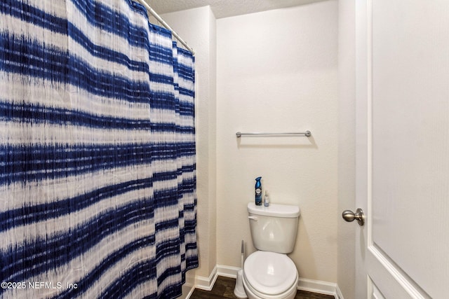 bathroom with toilet, hardwood / wood-style flooring, a textured ceiling, and curtained shower