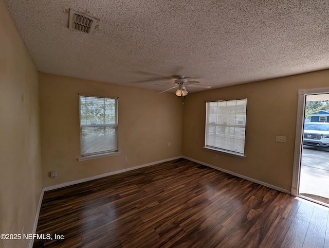 empty room featuring ceiling fan, dark wood-type flooring, and a textured ceiling