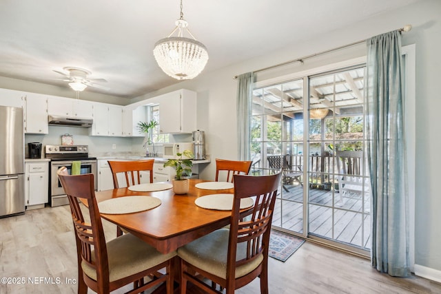 dining area with light hardwood / wood-style flooring, ceiling fan with notable chandelier, and sink