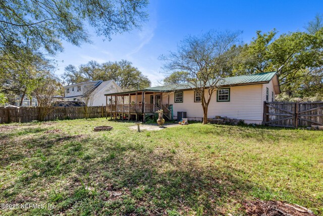 back of property featuring a yard, cooling unit, a fire pit, and a deck