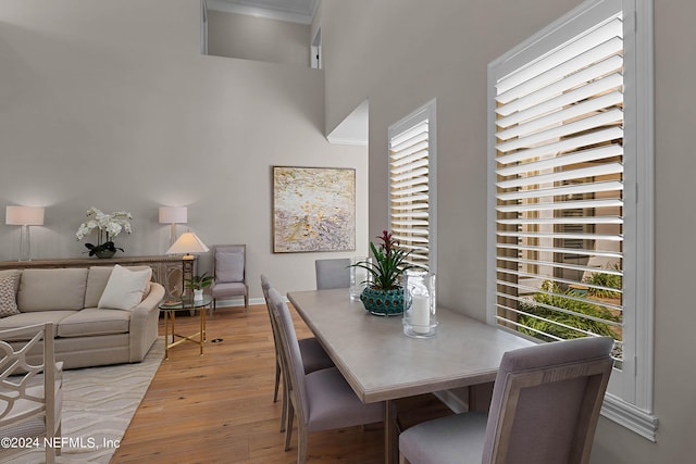 dining space with a towering ceiling and light hardwood / wood-style flooring