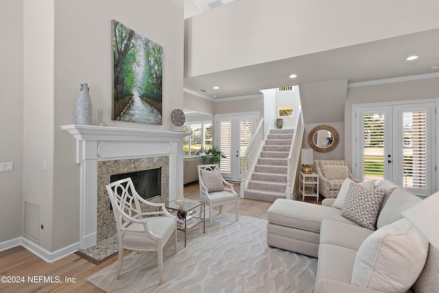 living room featuring a premium fireplace, a wealth of natural light, french doors, and light wood-type flooring