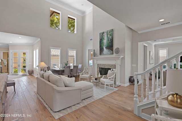 living room featuring crown molding, a wealth of natural light, and light wood-type flooring