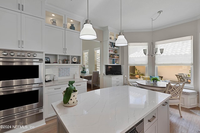 kitchen featuring stainless steel double oven, light stone countertops, and white cabinets