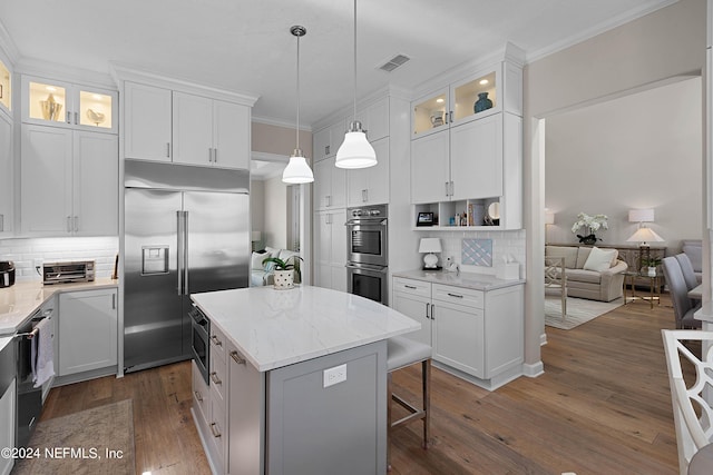 kitchen with stainless steel appliances, a center island, hanging light fixtures, and white cabinets