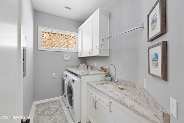 clothes washing area featuring sink, cabinets, and washer and dryer