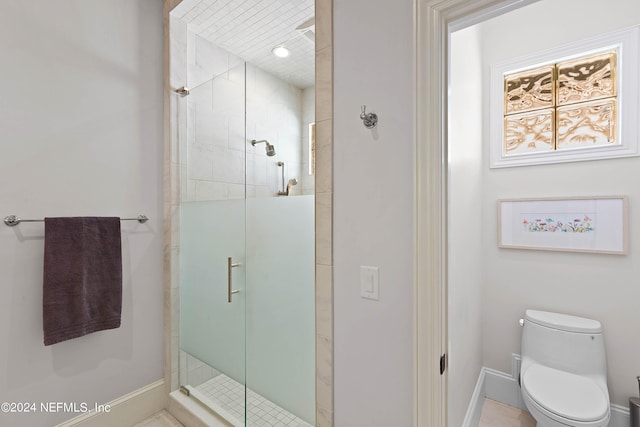 bathroom with a shower with shower door and toilet