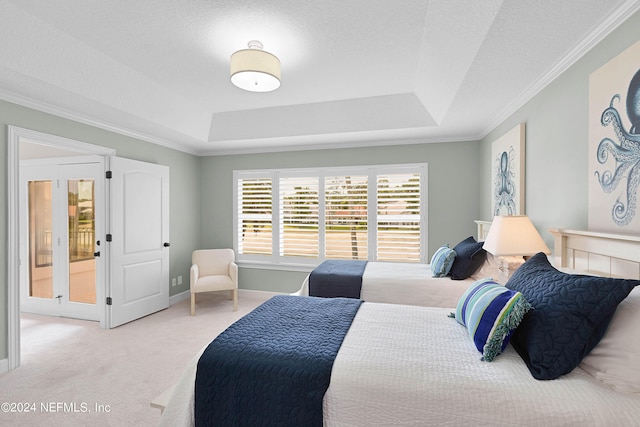 bedroom with carpet flooring, ornamental molding, a tray ceiling, and a textured ceiling