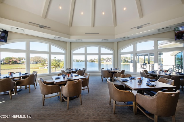 carpeted dining room with high vaulted ceiling and beamed ceiling