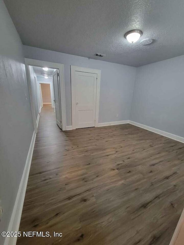 empty room with dark hardwood / wood-style flooring and a textured ceiling