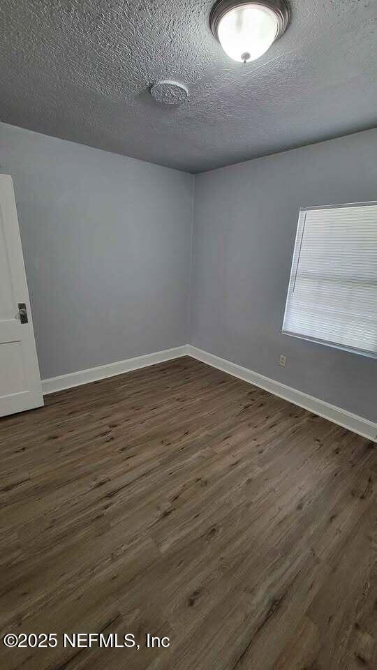 unfurnished room featuring a textured ceiling and dark hardwood / wood-style floors