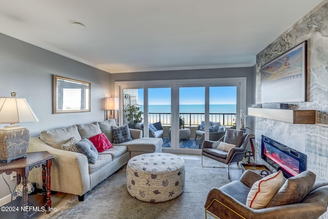 living room featuring a water view, plenty of natural light, crown molding, and a tiled fireplace