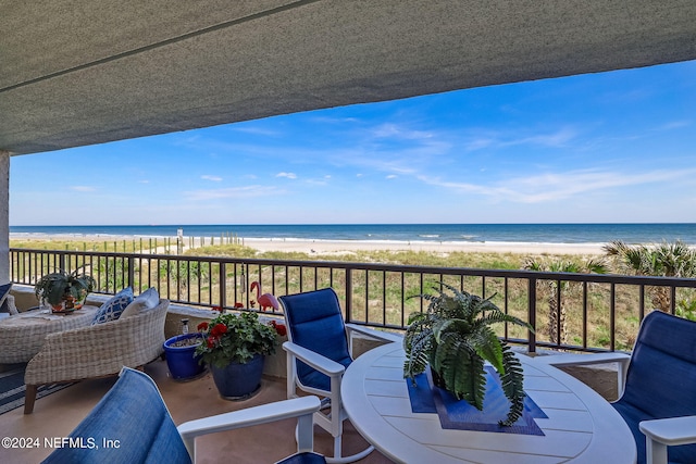 balcony with a water view and a view of the beach