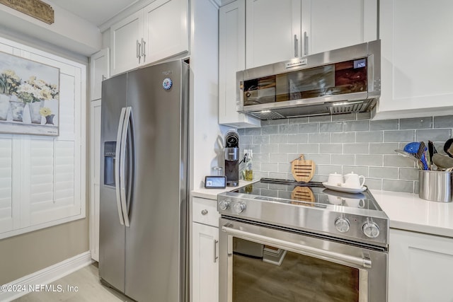 kitchen featuring decorative backsplash, appliances with stainless steel finishes, and white cabinets