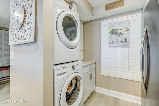 washroom featuring cabinets, stacked washer and dryer, and light hardwood / wood-style flooring