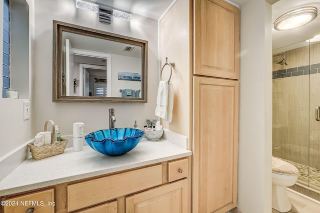 bathroom with vanity, toilet, and a shower with door