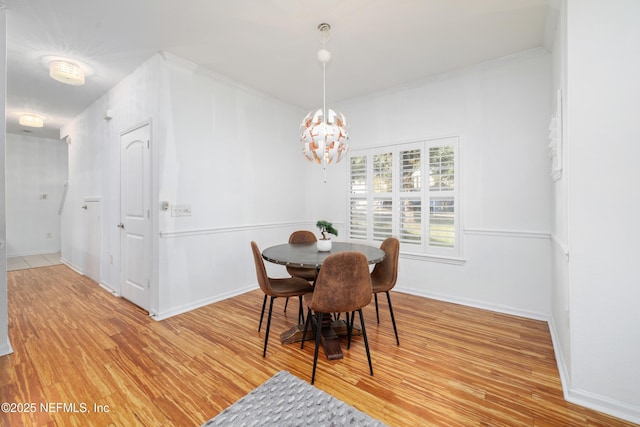 dining space featuring crown molding, a notable chandelier, and light wood-type flooring