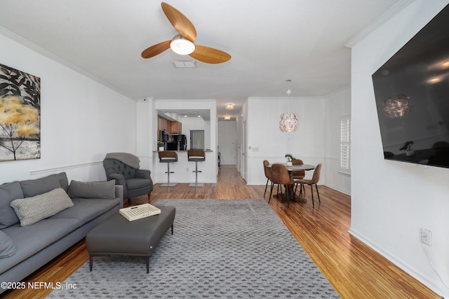 living room with ceiling fan, ornamental molding, and light hardwood / wood-style flooring