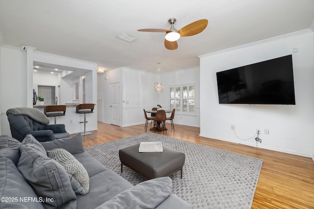 living room featuring ceiling fan, wood-type flooring, and ornamental molding