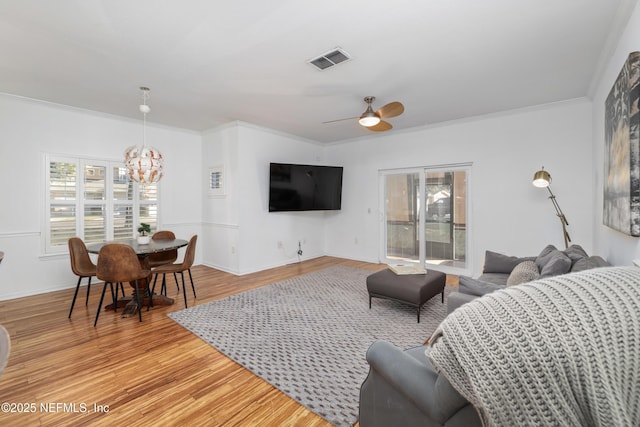 living room featuring crown molding, hardwood / wood-style floors, and ceiling fan with notable chandelier