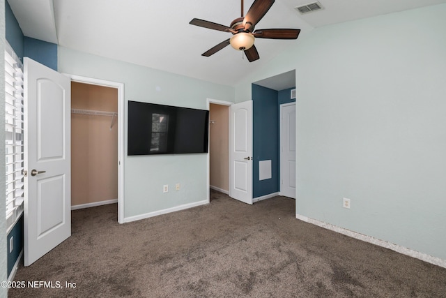 unfurnished bedroom featuring ceiling fan, a closet, vaulted ceiling, and dark colored carpet