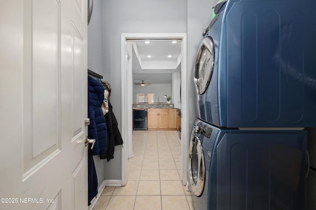 washroom with light tile patterned floors, stacked washer / dryer, and ceiling fan