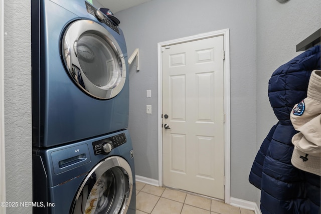 clothes washing area with light tile patterned floors and stacked washer and clothes dryer