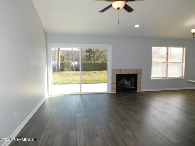 unfurnished living room with ceiling fan, dark hardwood / wood-style flooring, plenty of natural light, and a tiled fireplace