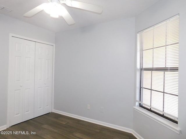 unfurnished bedroom featuring ceiling fan, dark hardwood / wood-style flooring, and a closet