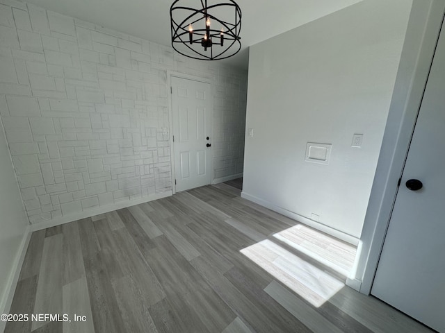 unfurnished dining area with light wood-type flooring and an inviting chandelier