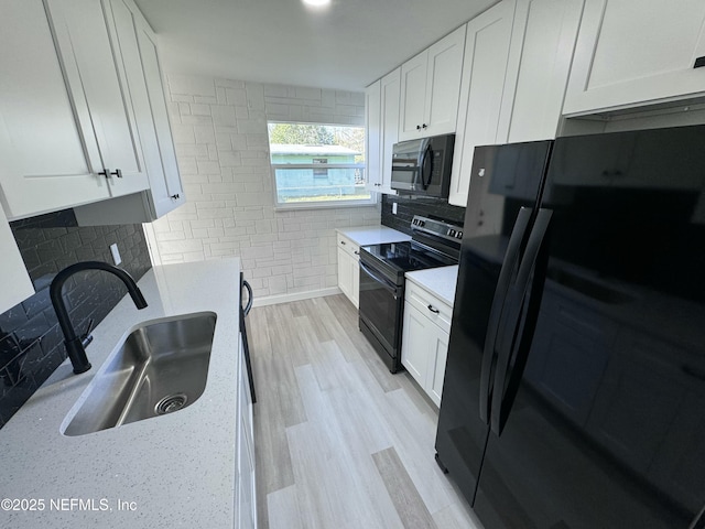 kitchen featuring light stone countertops, sink, white cabinetry, and black appliances