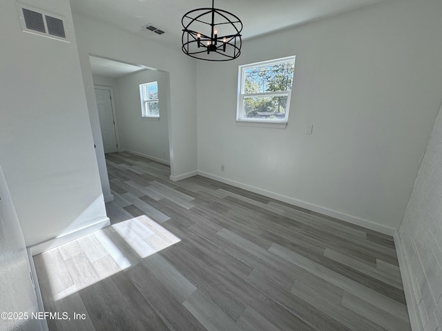 unfurnished dining area with light hardwood / wood-style floors, a wealth of natural light, and an inviting chandelier