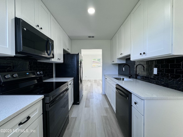 kitchen with white cabinets, sink, light hardwood / wood-style flooring, decorative backsplash, and stainless steel appliances